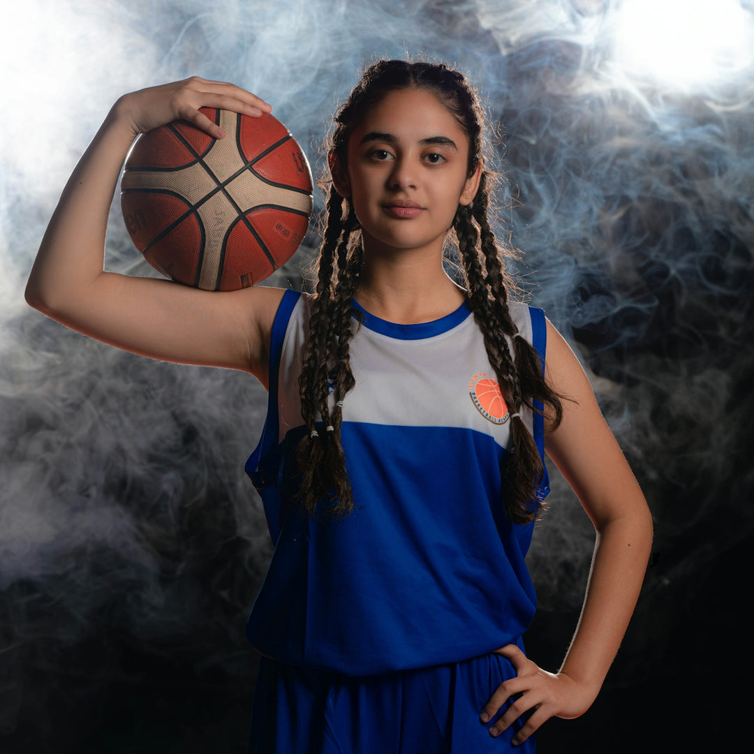 a girl in a blue and white uniform holding a basketball