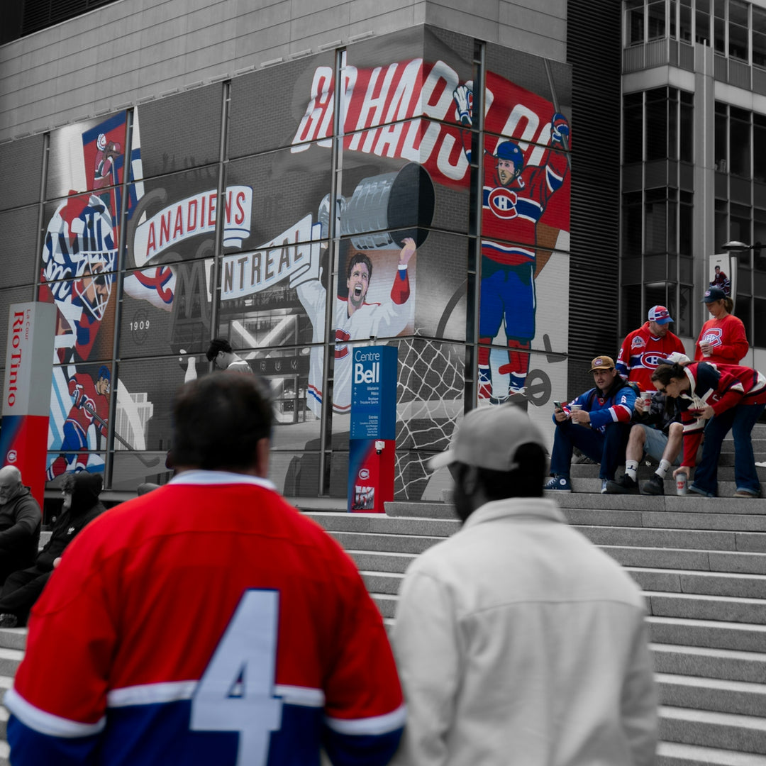 Fans in colorful hockey jerseys against a desaturated city backdrop.