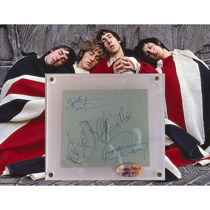Four men in Union Jack blankets rest against a wall; a signed paper is displayed in front.