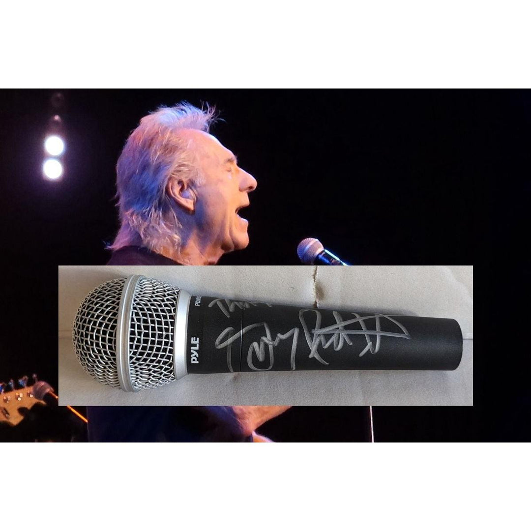 Man with white hair singing into a microphone; inset shows a signed black microphone.