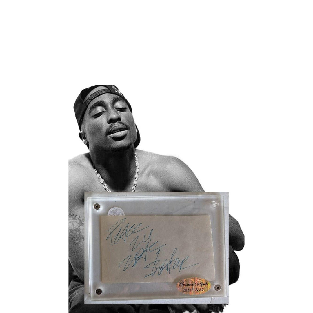Black and white portrait of a man with a headband, shirtless, holding a signed framed paper.