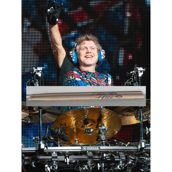 Drummer with headphones, arm raised, colorful shirt; surrounded by drum kit and cymbals.