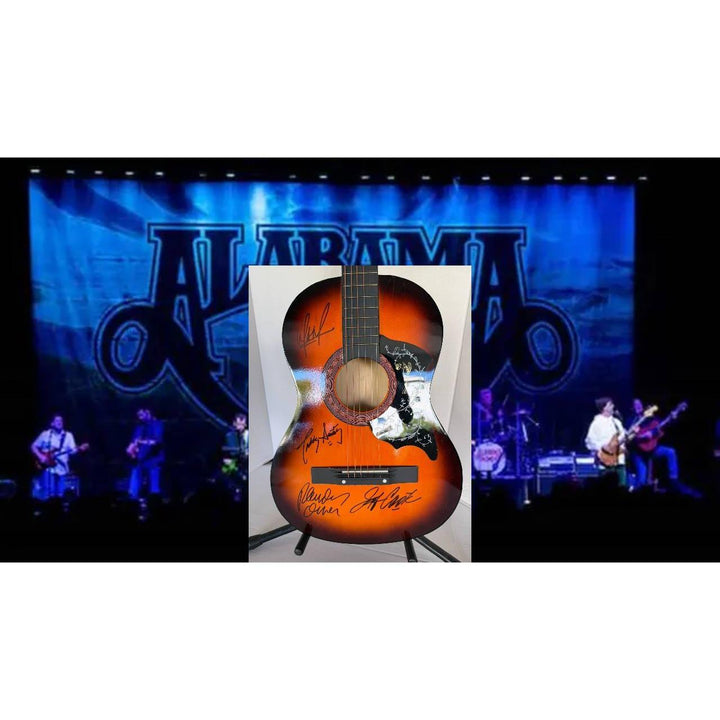 A signed orange acoustic guitar on stage with a blue backdrop and performers playing instruments.