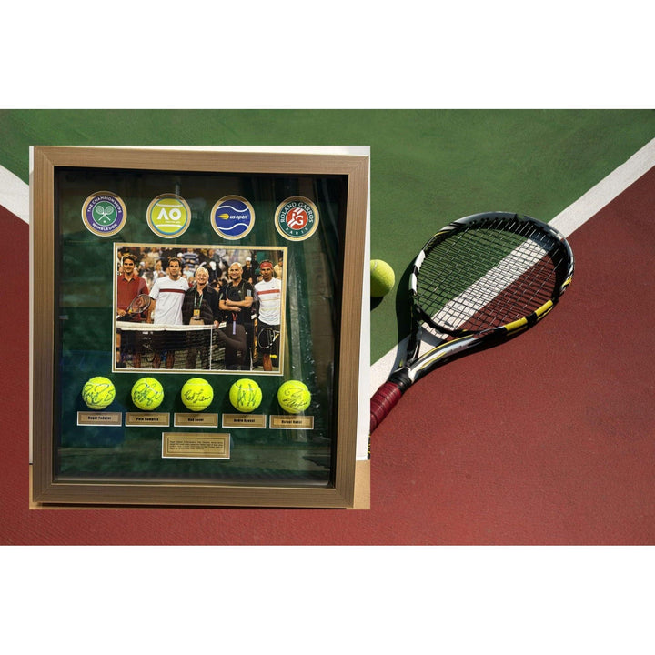 Framed tennis memorabilia with signed balls beside a racket on a green and red court.