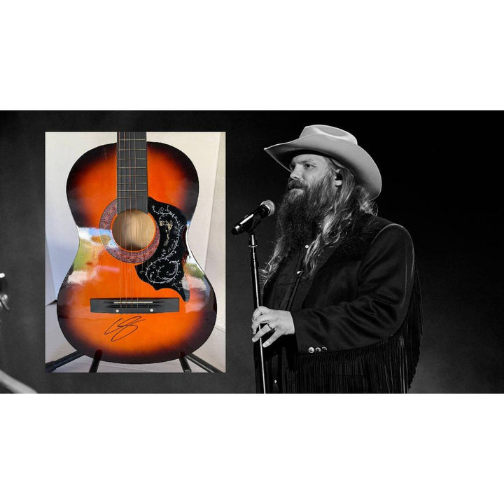 A man in a hat sings into a microphone; beside him, a signed orange acoustic guitar on display.