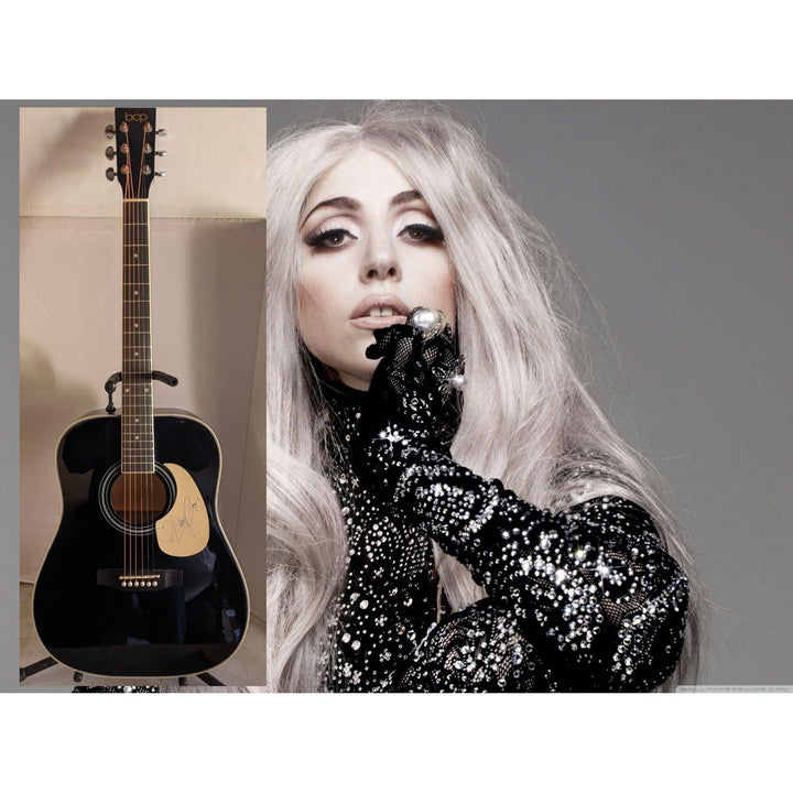 Black acoustic guitar beside a person with long silver hair, wearing sequined gloves.