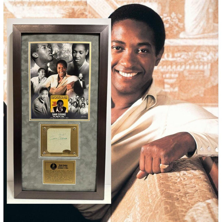 Portrait of a smiling man in a white shirt next to a framed collage and signed memorabilia.